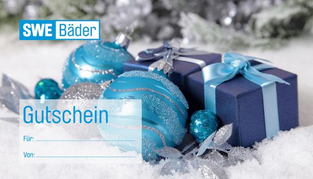 Aufnahme von einem Arrangement aus blauen Christbaumkugeln und kleinen Geschenkpäckchen auf Kunstschnee